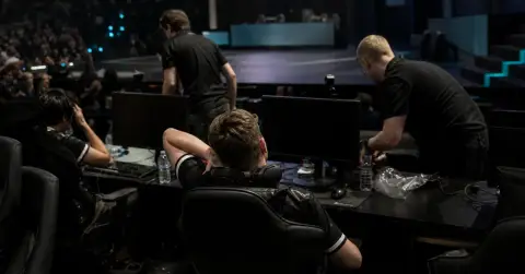 Anonymous esports players sit quietly at gaming PCs after a disappointing tournament result.
