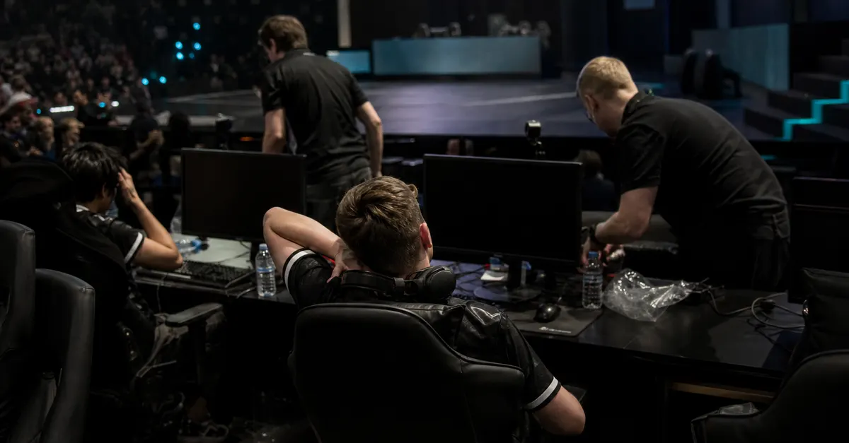 Anonymous esports players sit quietly at gaming PCs after a disappointing tournament result.