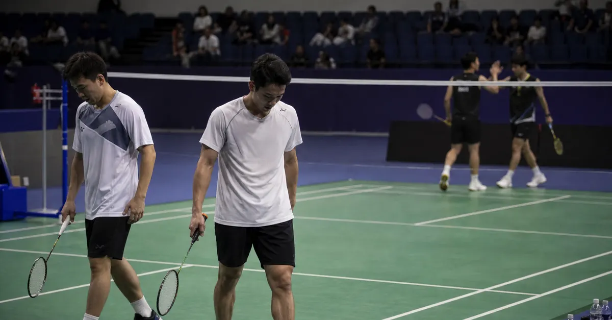 Two badminton players walk off court after a difficult final.