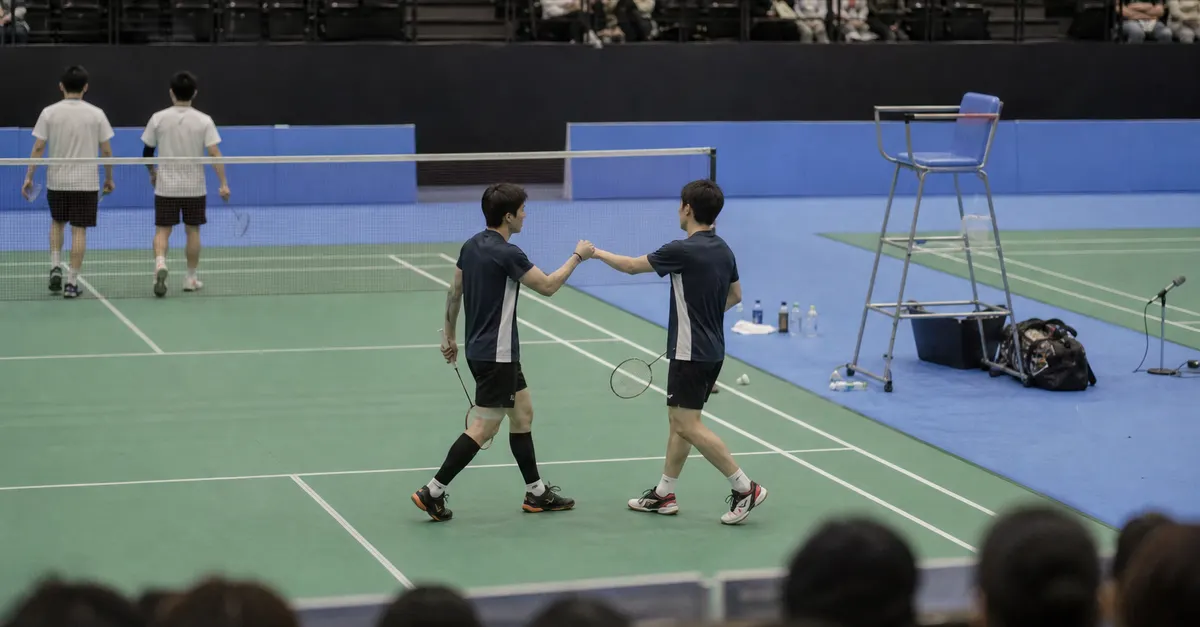 Anonymous badminton doubles players celebrate reaching a tournament semifinal after a straight-game win.