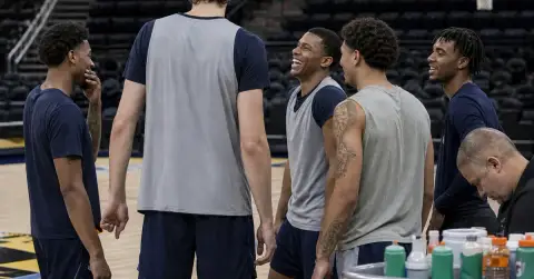 Tall anonymous basketball player joins teammates in a training-camp huddle.