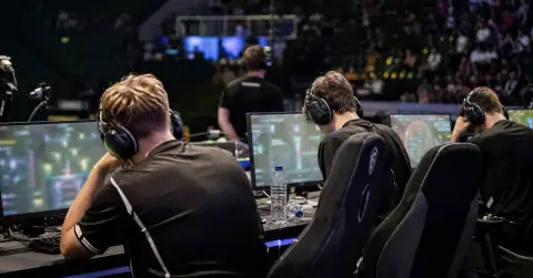 Esports players sit quietly at gaming PCs after a disappointing tournament finish.