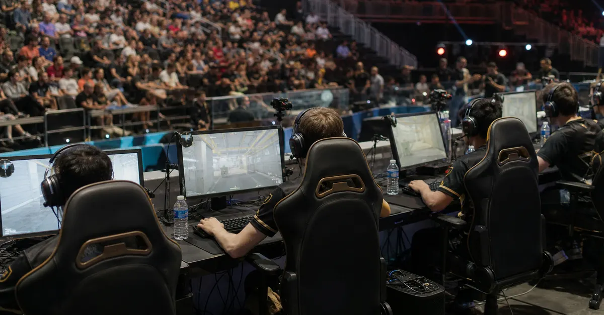 Anonymous esports players compete onstage at a packed arena event.