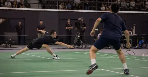 Two badminton players contest a fast rally across the net