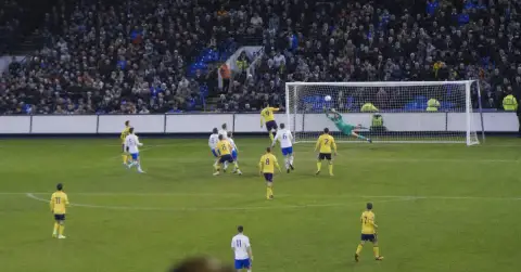 Anonymous footballer scores a late header as defenders and goalkeeper react