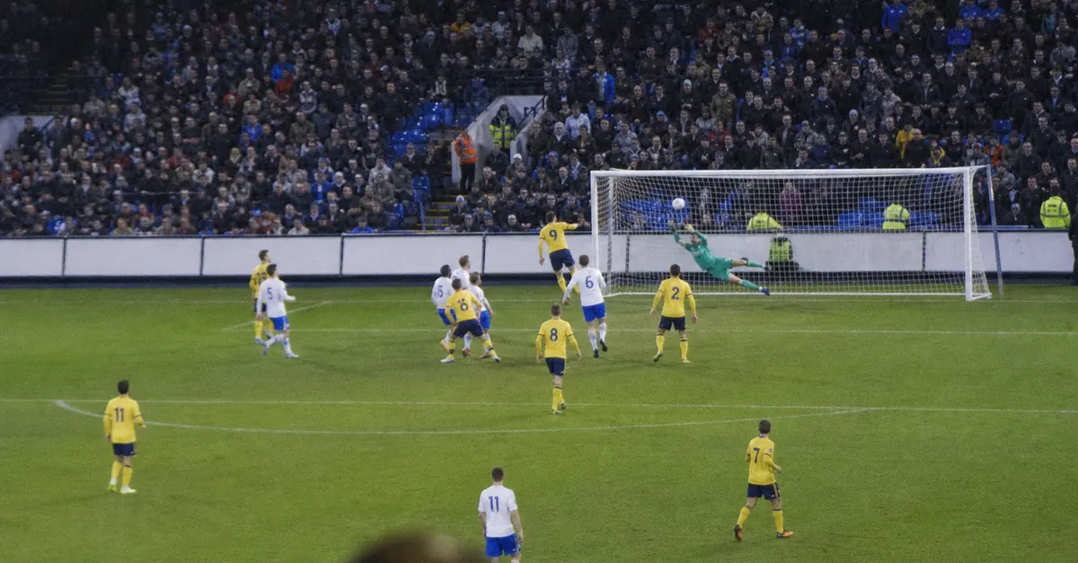Anonymous footballer scores a late header as defenders and goalkeeper react