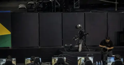 Anonymous esports players compete beside blank advertising panels in an arena.