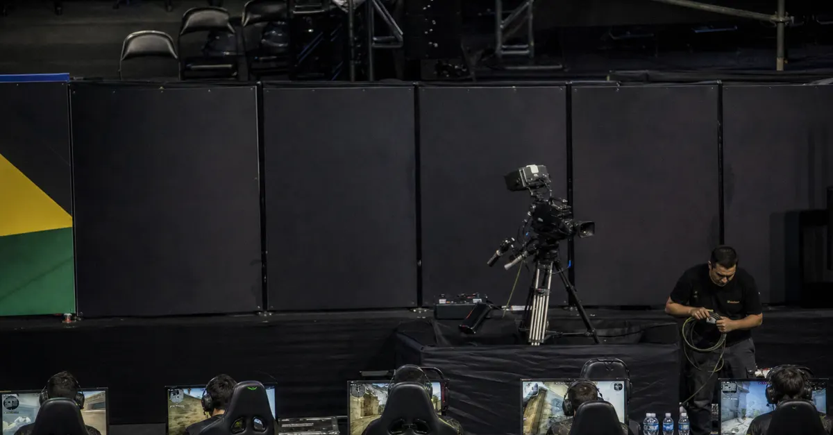 Anonymous esports players compete beside blank advertising panels in an arena.