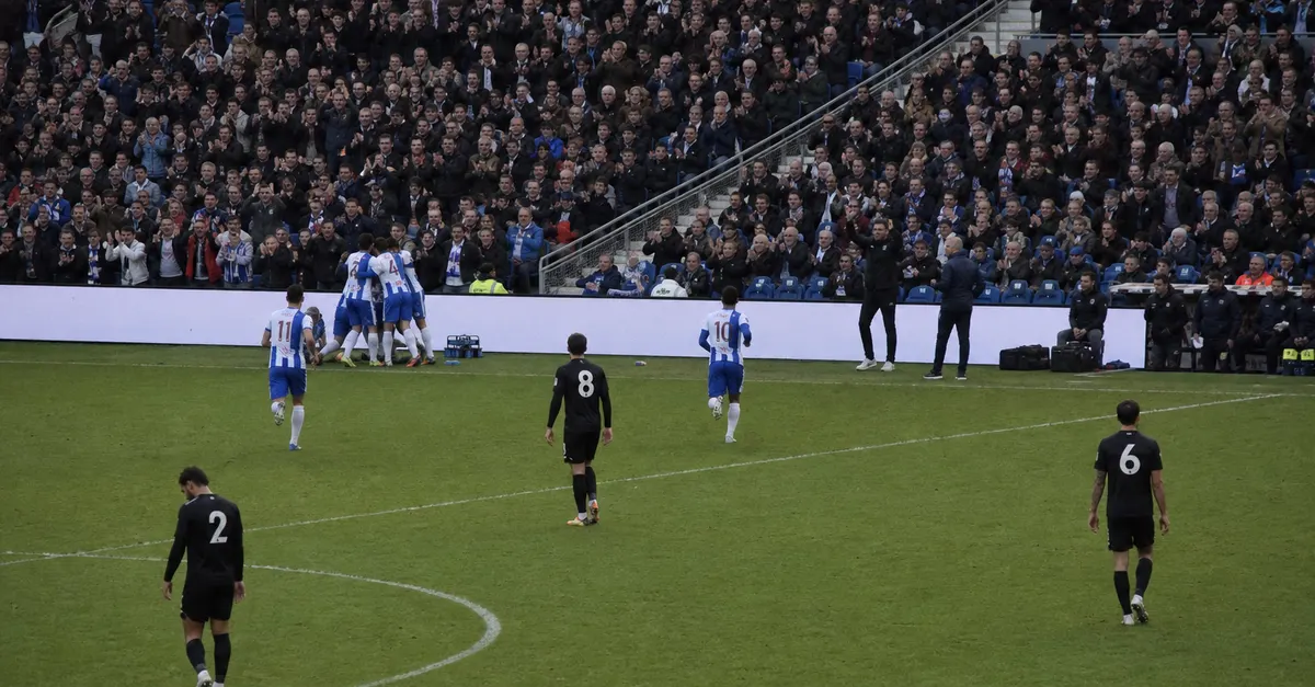 Anonymous footballers celebrate a goal as opponents return toward midfield.
