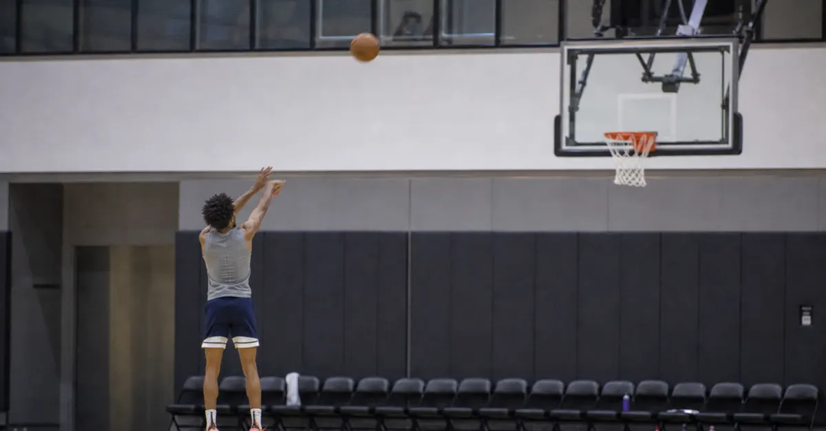 A lone anonymous basketball player practices on an empty professional court.