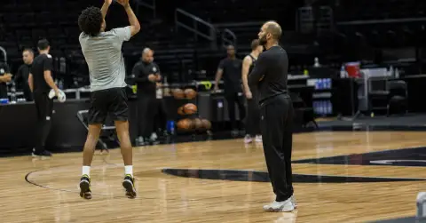 Anonymous basketball guard practices jump shots on a quiet court.