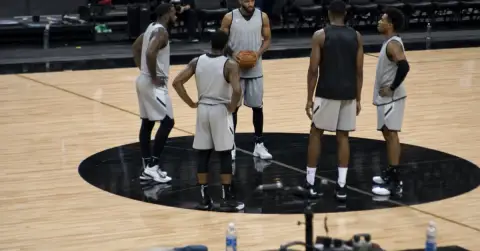 Anonymous basketball starters gather on court before a game.