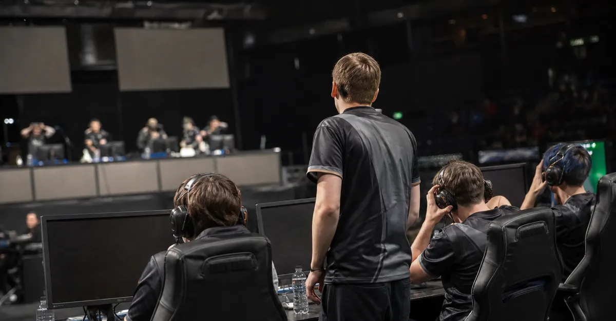Anonymous esports players finish a match at PCs under arena lights.