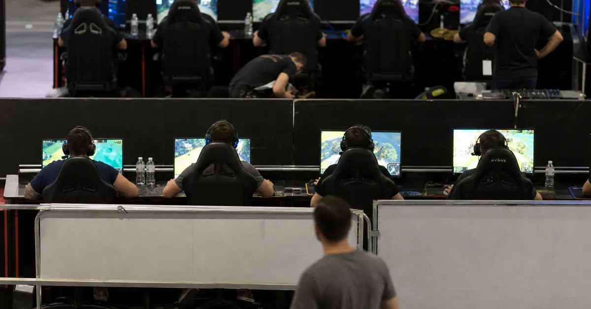 Two esports competitors play at separate partner qualification stations in an arena.