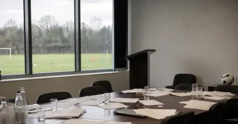 Empty football federation meeting room with paperwork, chairs and a ball