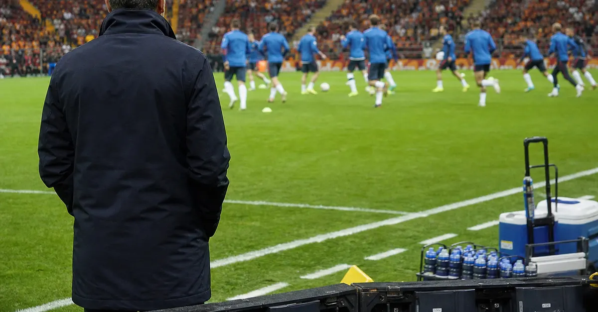 Anonymous coach watches players warm up before a European football match.