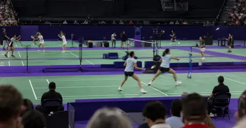 Malaysian badminton doubles players compete beneath arena lights during a major tournament.