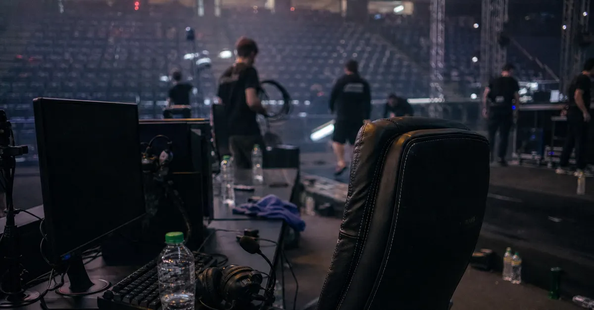 Empty esports commentary desk with a headset in a quiet arena.