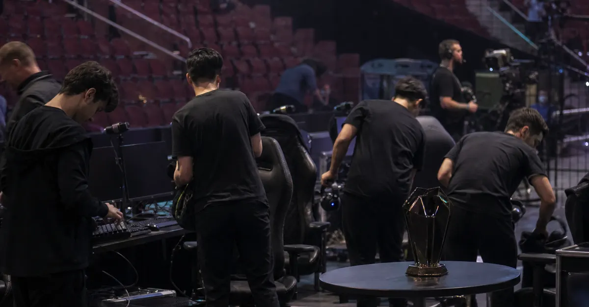 Anonymous esports players pack equipment beside empty gaming chairs after a tournament