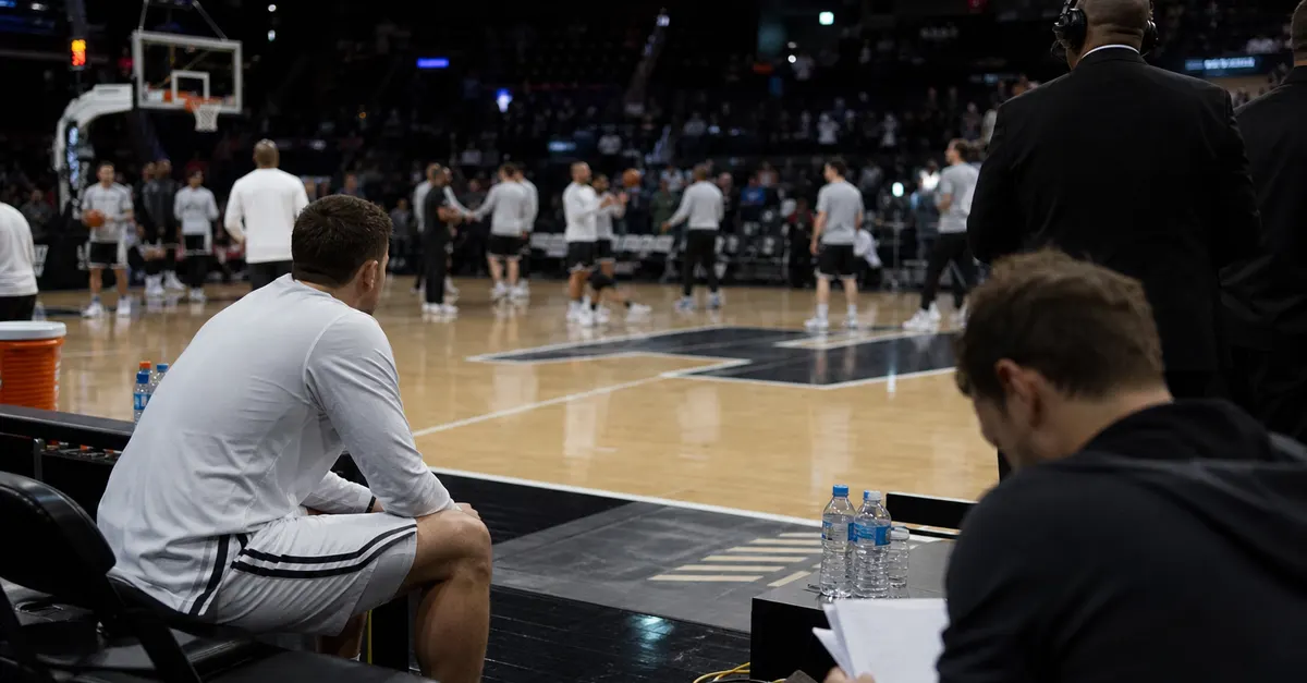 Anonymous basketball players warm up as a reporter reviews blank ranking pages.