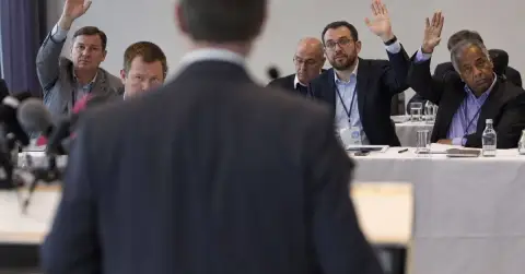 Anonymous football official addresses delegates in a plain press conference room