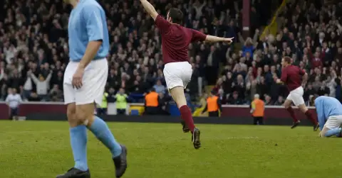 Anonymous striker celebrates as a defeated defender walks away on the pitch
