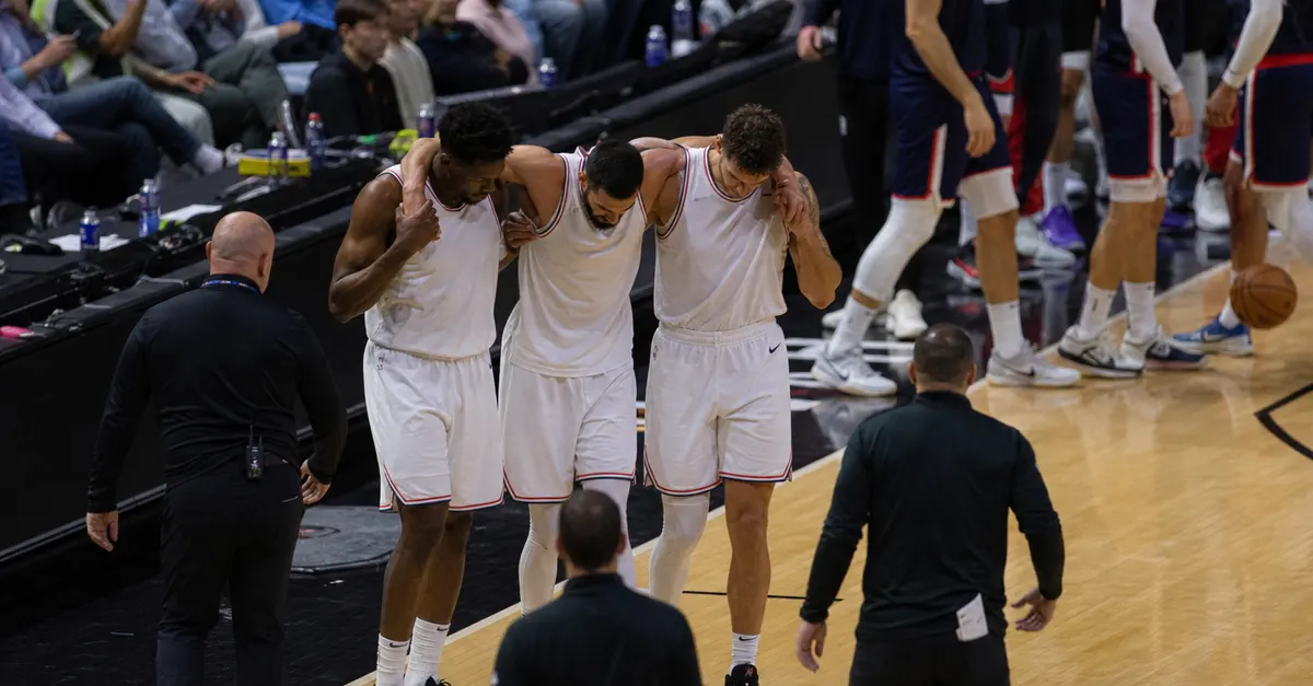 An injured basketball player is helped off court by teammates.