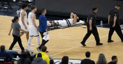 Injured basketball player carried from court on a stretcher