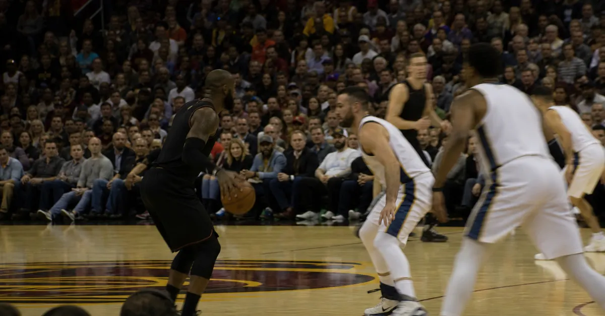 Anonymous basketball players compete during a crowded opening-night arena game.
