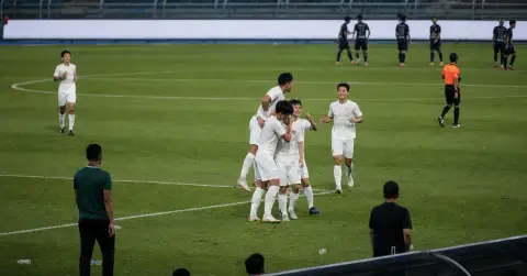 Anonymous footballers celebrate a goal during a night match in Malaysia.