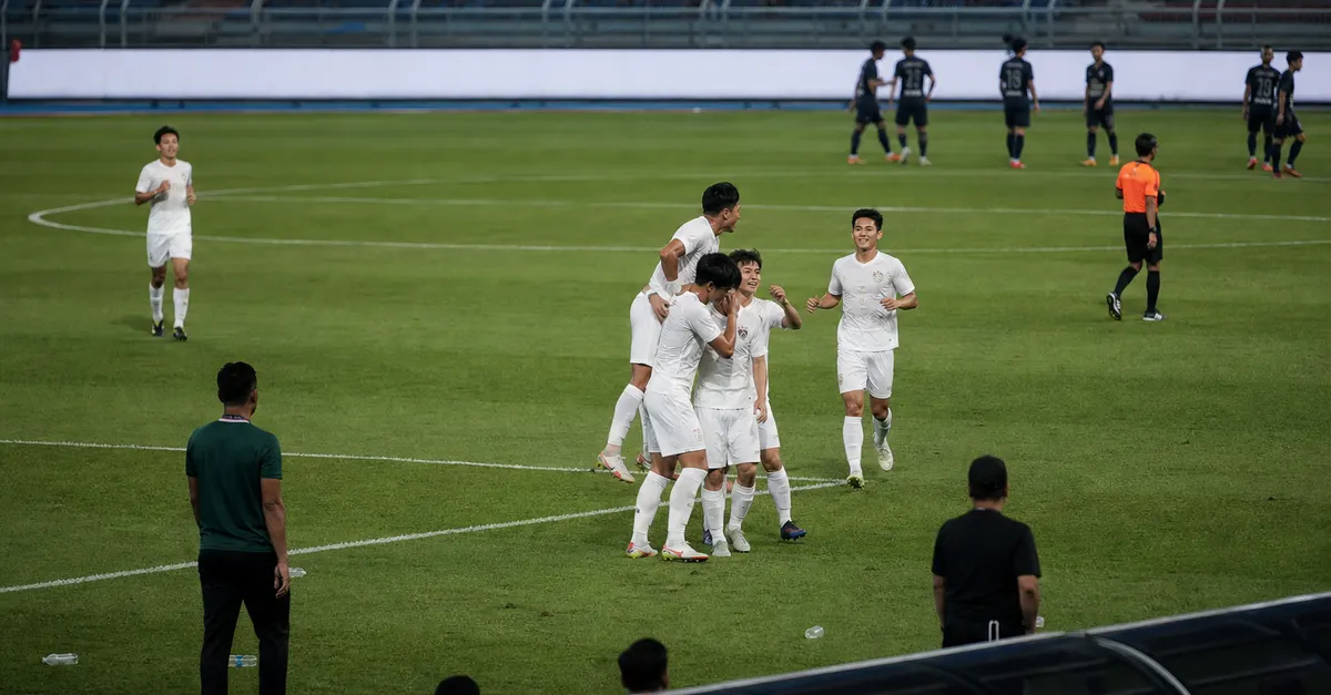 Anonymous footballers celebrate a goal during a night match in Malaysia.
