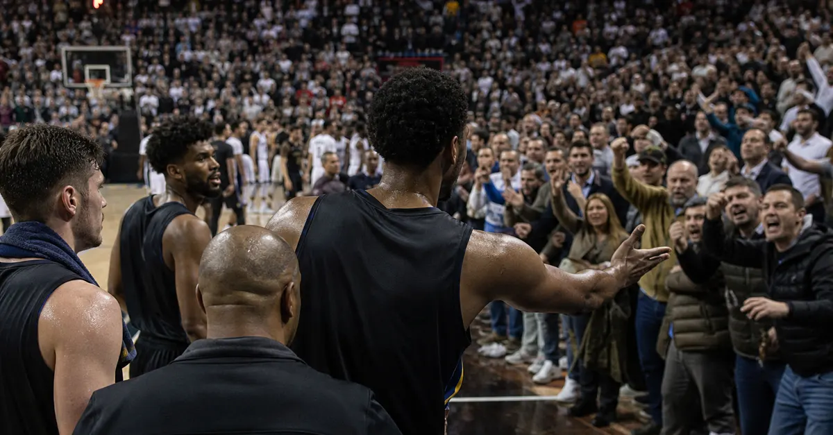Anonymous basketball player gestures toward jeering fans after an overtime comeback.