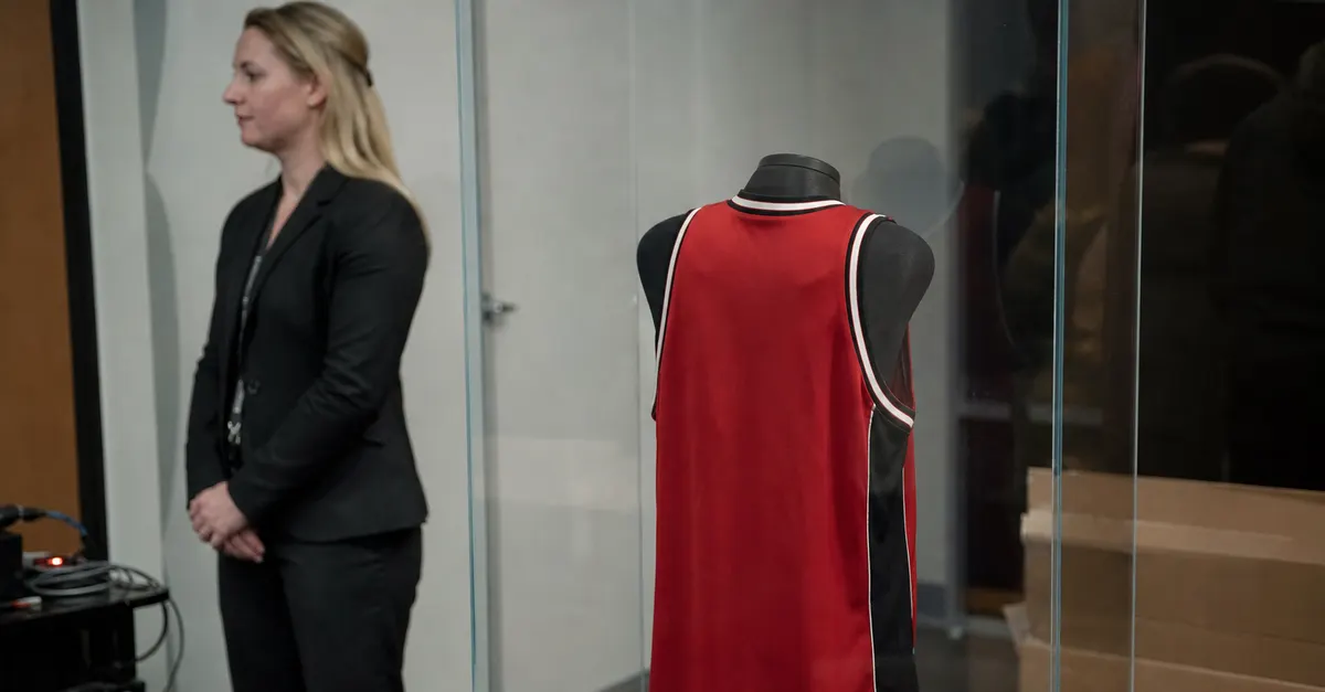 Vintage basketball jersey displayed behind glass at a private memorabilia viewing