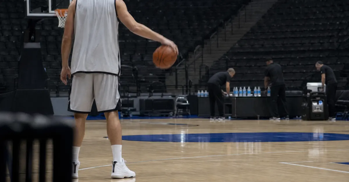 Anonymous basketball center practices while staff prepare an empty arena.