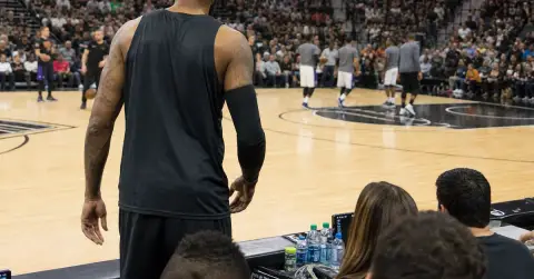 Veteran basketball player warms up as opponents gather before a season opener.