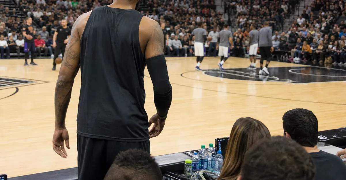 Veteran basketball player warms up as opponents gather before a season opener.