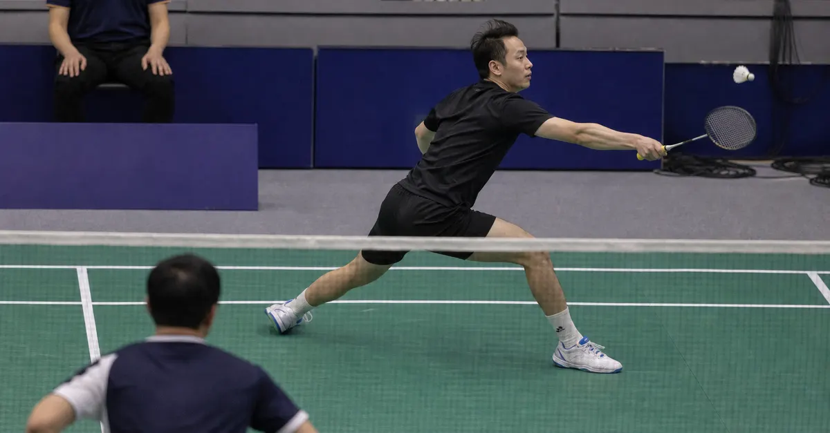 An anonymous badminton player returns a shuttle during an indoor match.