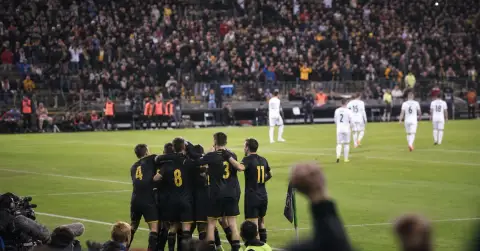 Anonymous footballers celebrate a late comeback as opponents leave the pitch.