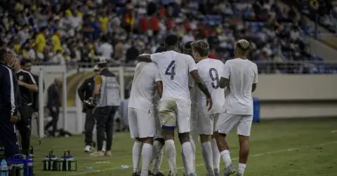 Anonymous footballers gather after a hard-fought international match under stadium lights.