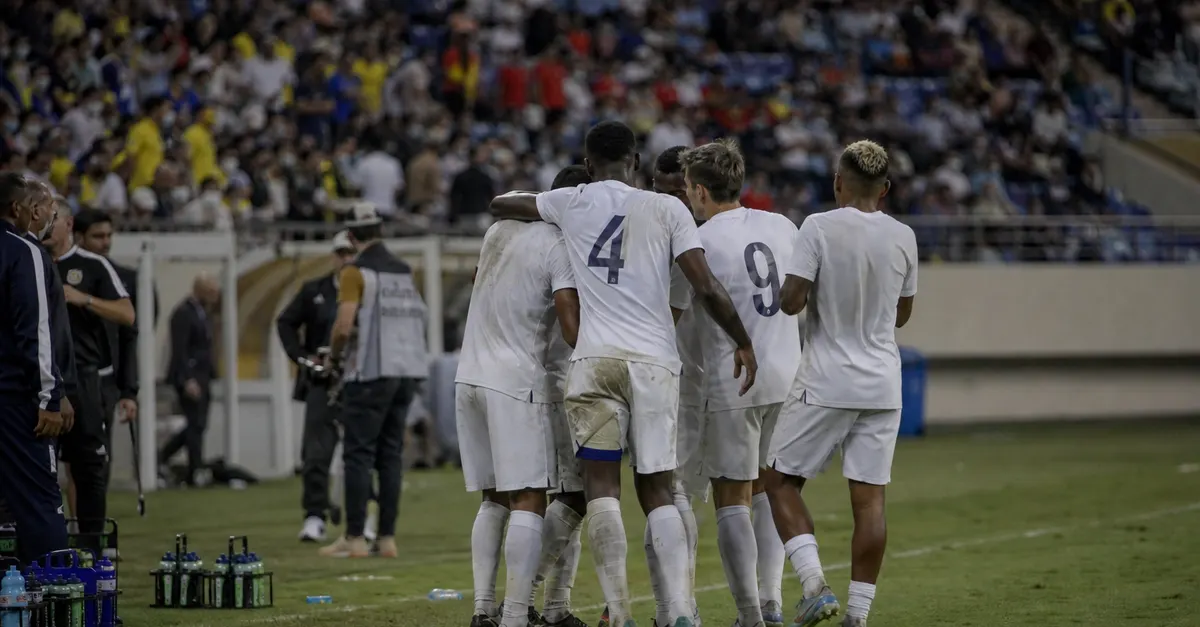 Anonymous footballers gather after a hard-fought international match under stadium lights.
