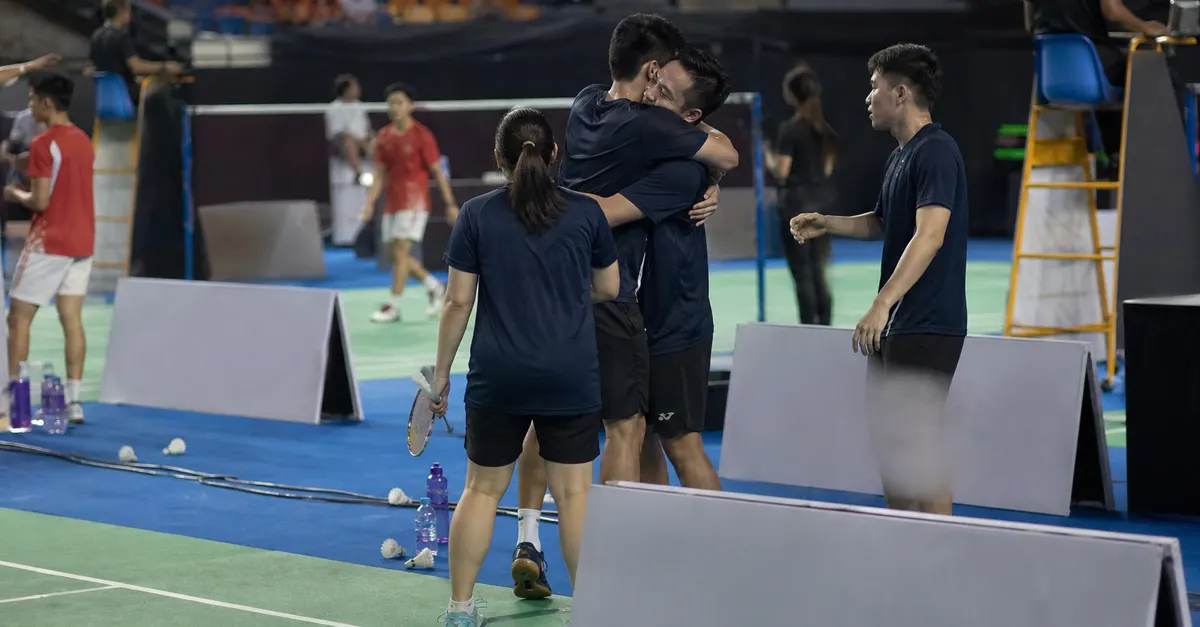 Anonymous badminton players celebrate a team victory beside the court