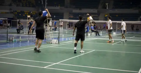 Anonymous badminton players celebrate a point on an indoor court