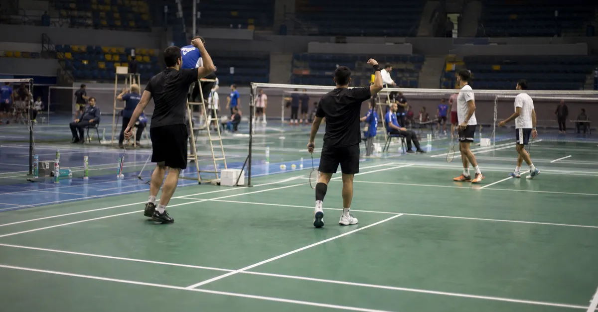 Anonymous badminton players celebrate a point on an indoor court