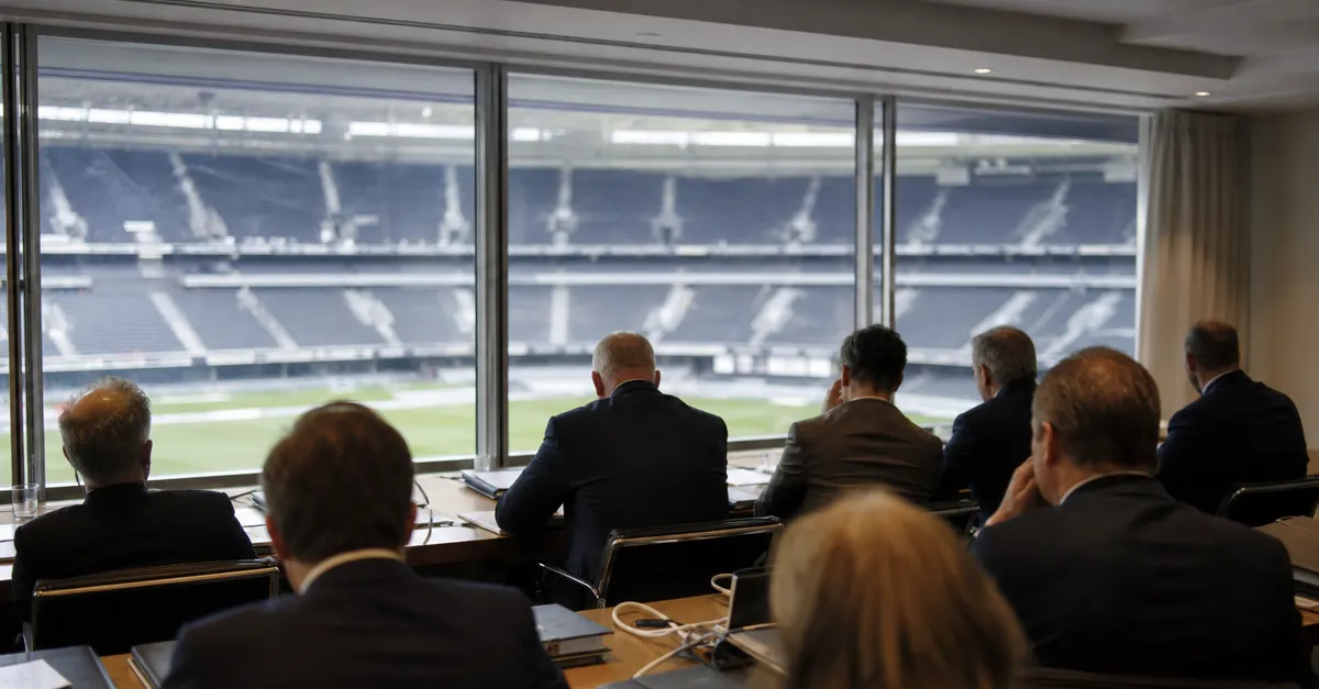 Anonymous officials meet beside a view of an empty football stadium