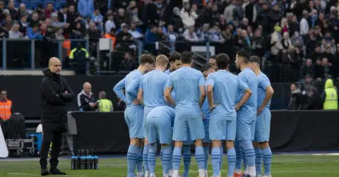 Anonymous football players huddle before a match at a stadium.