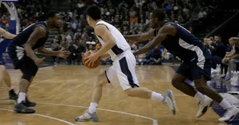 Anonymous basketball guard drives toward the basket as defenders converge