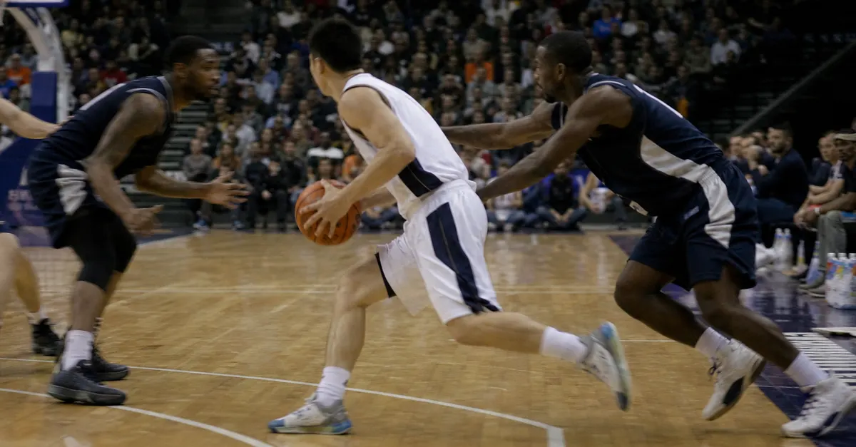 Anonymous basketball guard drives toward the basket as defenders converge