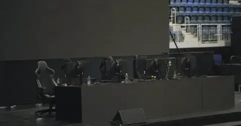 Empty esports stage with gaming PCs and headsets after an event.