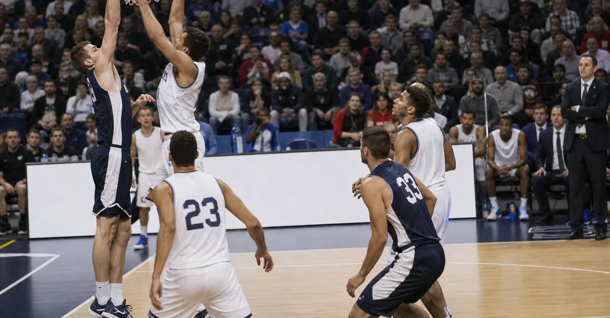 Anonymous basketball players battle for a rebound in a tense arena.