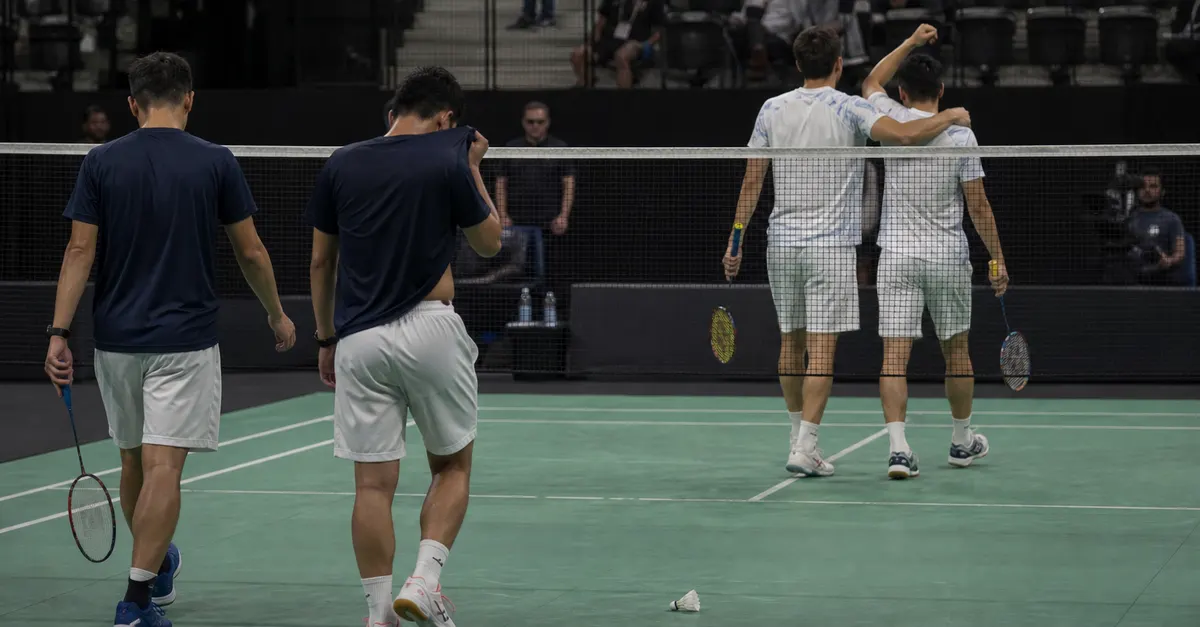 Badminton doubles players regroup at the net after a close match.